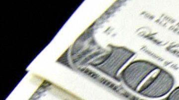 A money changer holds a wad of USD bills