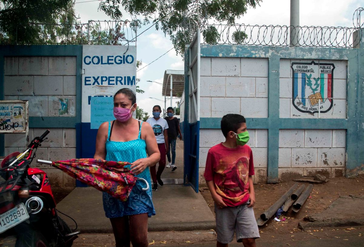 Una mujer junto a su hijo (d) utilizan tapabocas al salir de una escuela pública este viernes, en Managua. 