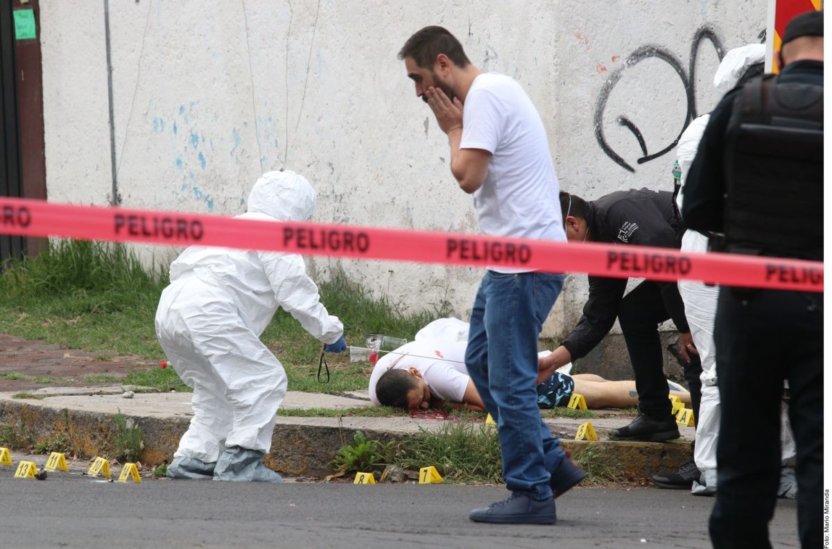 Elementos de la fiscalía de Ciudad de México levantan el cuerpo de uno de los hombres asesinados .