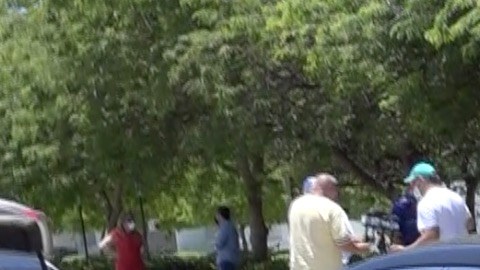 Una mujer deposita una bolsa con comida en un auto en Miami.
