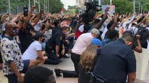 El jefe de la Policía de Houston Art Acevedo (centro) hincado en una de las manifestaciones.
