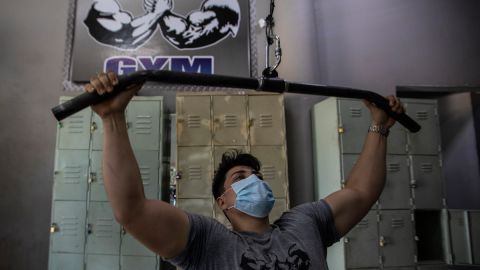 Un hombre haciendo ejercicio en un gimnasio con mascarilla.