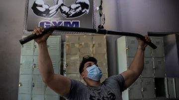 Un hombre haciendo ejercicio en un gimnasio con mascarilla.