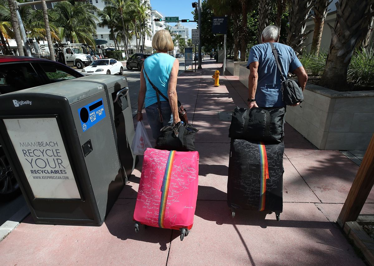Turistas cargando maletas en Miami Beach.