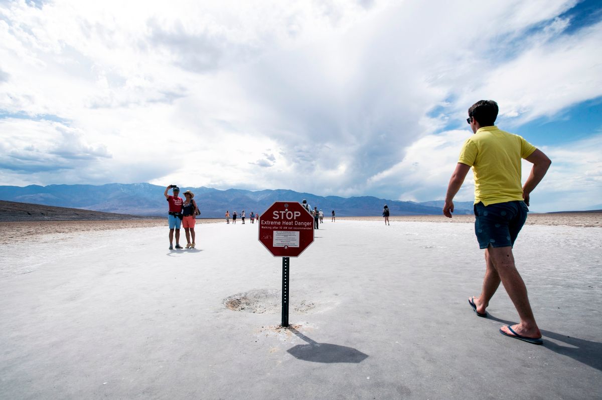 Visitantes cerca del aviso con la advertencia de calor extremo en el Valle de la Muerte.