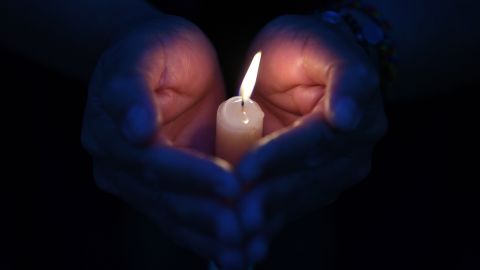 An anti-government demonstrator puts her hands around a candle as she takes part in a day of vigils and prayers called by Venezuelan opposition leader and self-proclaimed interim president Juan Guaido, in eastern Caracas, on May 5, 2019. - Venezuela's Constituent Assembly, which rules the South American country with absolute powers, plans to strip parliamentary immunity from opposition lawmakers who backed a failed uprising this week, leader Diosdado Cabello said Sunday. (Photo by Ronaldo SCHEMIDT / AFP)        (Photo credit should read RONALDO SCHEMIDT/AFP via Getty Images)