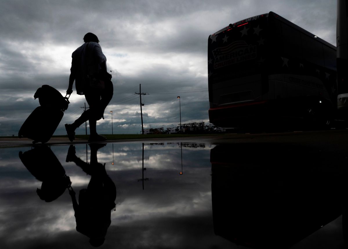 Una mujer lleva sus pertenencias hacia un autobús de evacuación antes de la llegada del Huracán Laura a Louisiana.