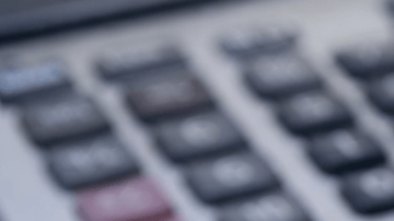 Amuletos de prosperidad como elefante dorado, monedas chinas y hojas de laurel sobre billete y cuaderno