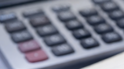 Amuletos de prosperidad como elefante dorado, monedas chinas y hojas de laurel sobre billete y cuaderno