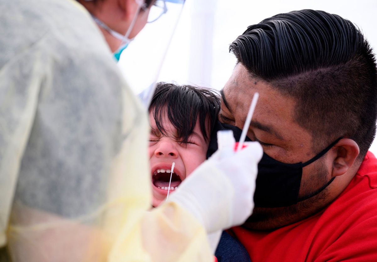 Un padre y un niño hispanos se realizan la prueba de COVID-19 al sur de Los Angeles.