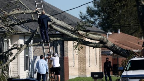 Vecinos qitan un árbol que cayó sobre una casa en Chalmette, Louisiana.