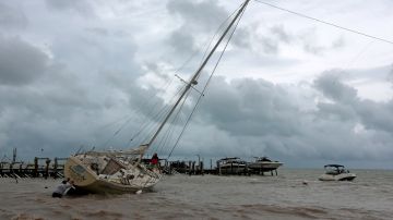 Un hombre empuja una embarcación encallada en Cancún, debido a la tormenta Gamma.
