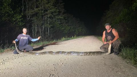 Los dos cazadores posan con la pitón que encontraron en los Everglades, en Florida.