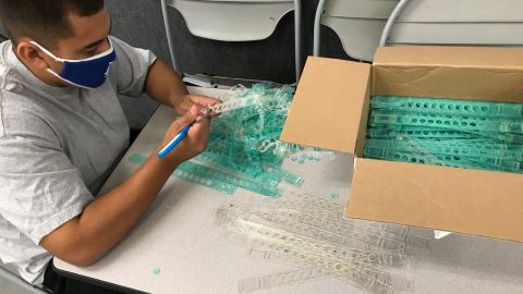 Jóvenes trabajan armando protectores faciales. (Suministrada)