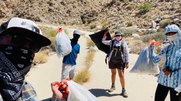 Los voluntarios muestran las bolsas de ropa que dejan en diversos caminos del desierto.