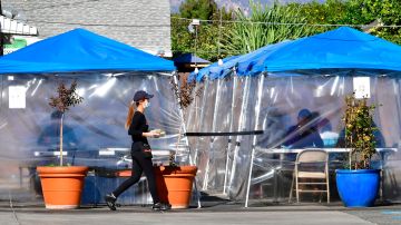 Una mesera hace entrega de pedidos en el área exterior de un restaurante cerca de Los Ángeles.