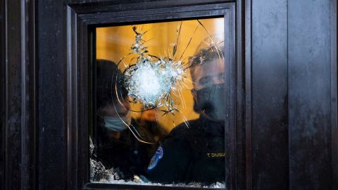 WASHINGTON (ESTADOS UNIDOS), 06/01/2021.- Dos policías observan a través del vidrio roto de una de las puertas del Capitolio de Estados Unidos, luego de que seguidores de Donald Trump irrumpieran en el recinto durante unas protestas hoy, en Washington (Estados Unidos). Los manifestantes a favor de Donald Trump irrumpieron en el Capitolio de los Estados Unidos donde tuvo lugar la certificación de voto del Colegio Electoral para el Presidente electo Joe Biden. EFE/ MICHAEL REYNOLDS