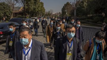 Funcionarios chinos salen de una conferencia de prensa donde se alojan miembros de la Organización Mundial de la Salud, en Wuhan, China, para conocer el origen del coronavirus.
