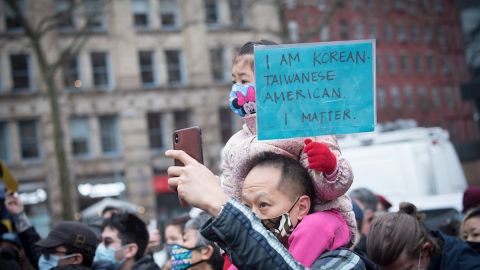 Hombre asiático carga a una niña en protesta contra agresiones