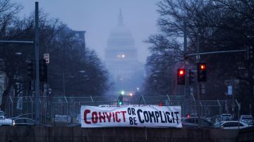 Un letrero que dice 'Condenar o ser cómplice' cuelga de un puente en Washington D.C.