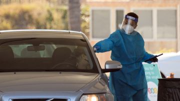 Un enfermero vacuna a una persona a través de la ventana del auto.