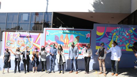 Marcela Celorio (c) corta el listón para develar el mural “Gratitud” que realza la labor de los trabajadores esenciales.