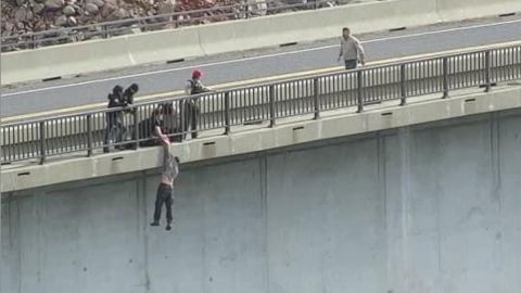 El agente Andrew Long sostiene en el aire a un suicida que saltó de un puente en California.