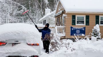 Un vecino limpia de nieve su auto en Wilmington, Massachusetts.