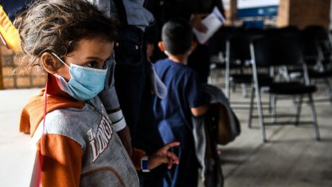 Una niña migrante con su madre esperan un autobús cerca del Puente Internacional Gateway en Texas.