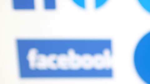 Mano sosteniendo teléfono celular con imagen de Facebook