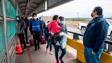 Mujer con niña en brazo cruzando frontera con EE.UU.