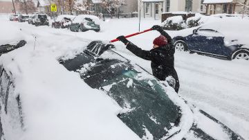 Hombre retira nieve de auto