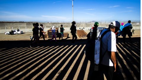 Migrantes en muro fronterizo