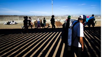 Migrantes en muro fronterizo