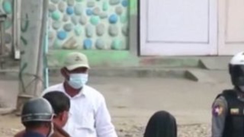 La monja Ann Rose Nu Tawng arrodillada frente a varios policías para proteger a unos niños y residentes.