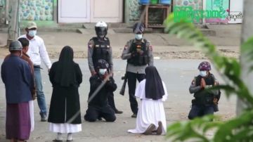 La monja Ann Rose Nu Tawng arrodillada frente a varios policías para proteger a unos niños y residentes.