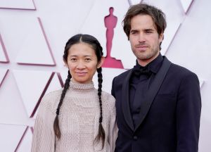 Chloe Zhao llegó con sus acostumbradas trenzas en el cabello y acompañada de Joshua James Richards. Foto: Chris Pizzello-Pool/ Getty Images.