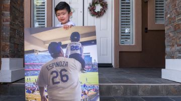 Ezekiel Espinoza sostiene una fotografía de su primer partido de los Dodgers de Los Angeles junto a su padre.  (Heidi de Marco/KHN)