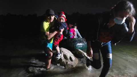 Un coyote carga a un niño inmigrante luego de cruzar el Río Grande en un bote.