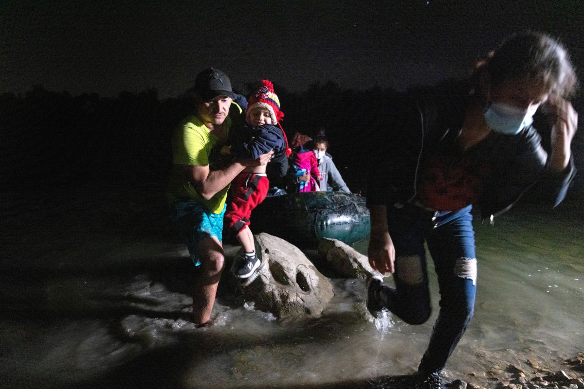 Un coyote carga a un niño inmigrante luego de cruzar el Río Grande en un bote.