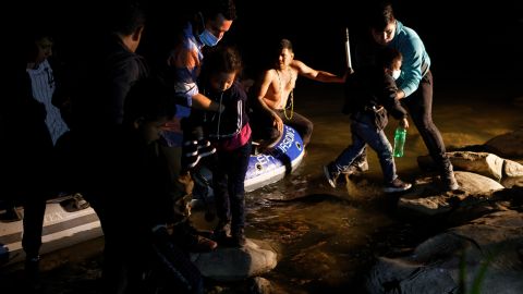 Un traficante (c) trae familias de inmigrantes a través del Río Grande.