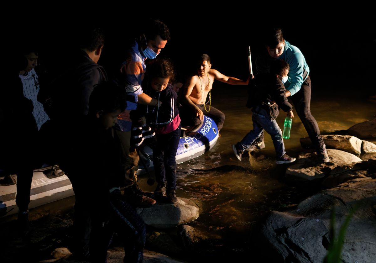 Un traficante (c) trae familias de inmigrantes a través del Río Grande.