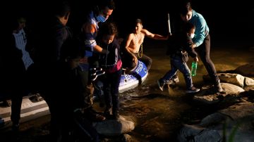 Un traficante (c) trae familias de inmigrantes a través del Río Grande.