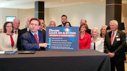 Ron DeSantis  enseña un cartel sobre las elecciones después de la firma de la SB90.