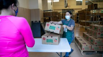 La gerente de servicio de alimentos Nakheu Saephanh entrega cajas de comida a los miembros de una familia en La Escuelita en Oakland el 7 de junio de 2021.