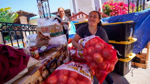 La voluntaria de la "Mesa de Justicia y Esperanza", Marcela, carga una bolsa de cebollas.