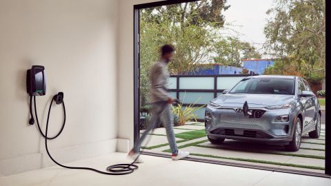 Foto de un hombre iniciando el proceso de carga de su vehículo eléctrico con una estación doméstica de Electrify America