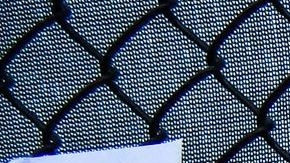 Un hombre usa su teléfono mientras mira fotos de residentes desaparecidos del edificio derrumbado en Surfside.