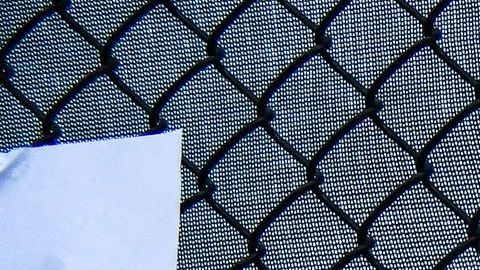 Un hombre usa su teléfono mientras mira fotos de residentes desaparecidos del edificio derrumbado en Surfside.