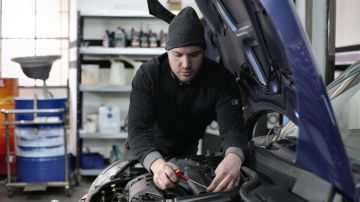 Foto de un mecánico revisando el motor de un auto